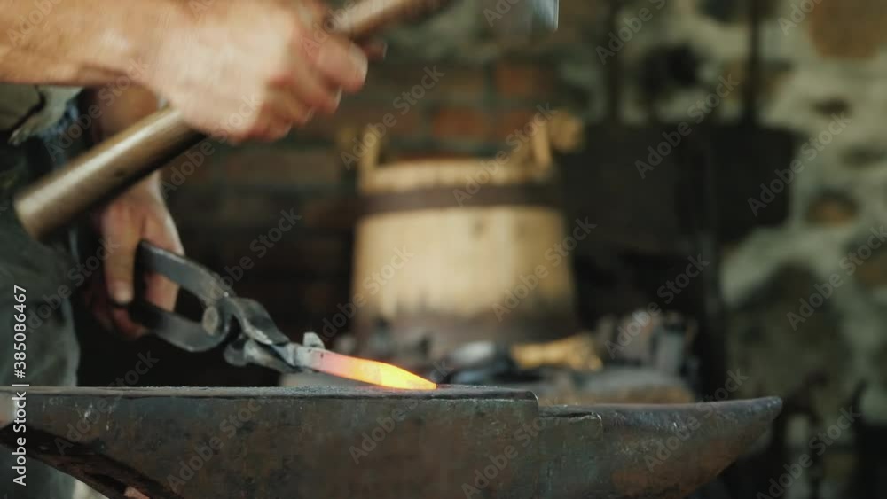 A blacksmith with forceps holds a red-hot billet above the anvil, striking it with a hammer. Traditional crafts A blacksmith with forceps holds a red-hot billet above the anvil, striking it with a hammer. Traditional crafts
