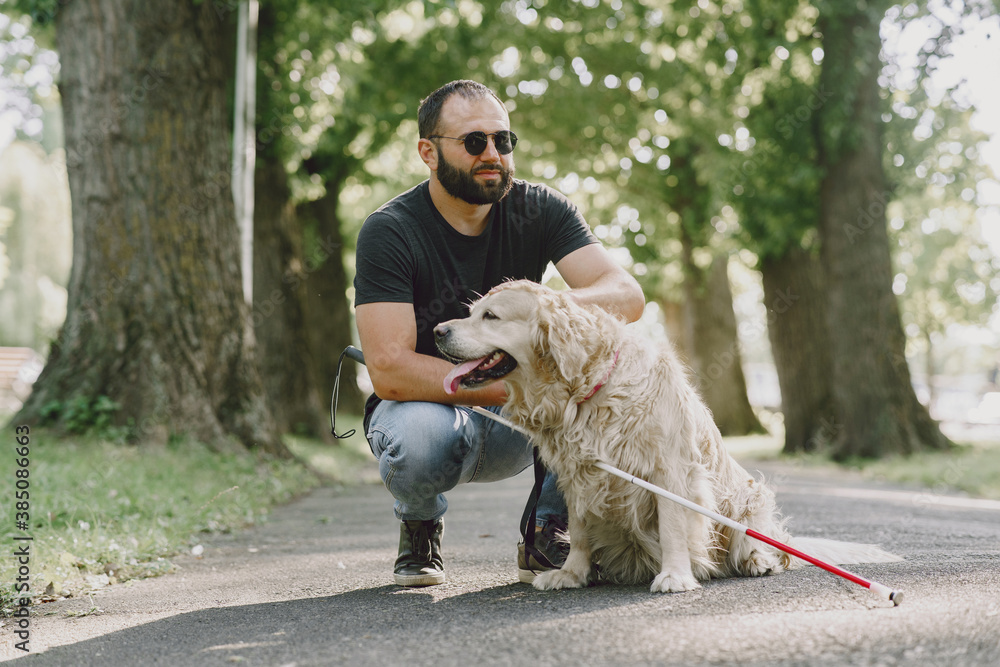 Guide dog helping blind man in the city. Handsome blind guy have rest with golden retriever in the city. Guide dog helping blind man in the city. Handsome blind guy have rest with golden retriever in the city.