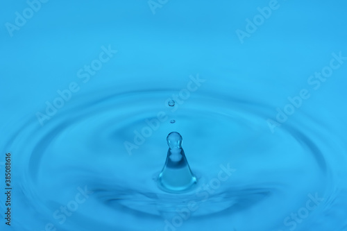 Drop falling on the water surface close up with circles on the water