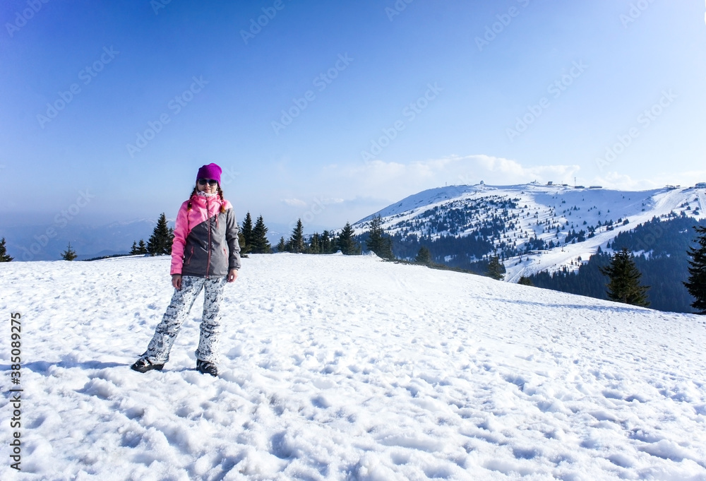 Smiling girl on the Kopaonik ski slope in ski clothes. Beautiful mountain view, winter landscape. Active lifestyle. Young woman