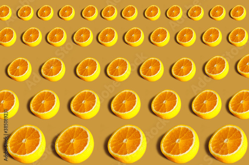 Fototapeta Naklejka Na Ścianę i Meble -  Lemons pattern. Repeating round half of lemon on an orange background. Lots of lemon halves on an orange surface. Horizontal. The concept of healthy food and vegetarianism.