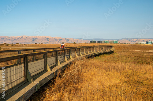 Unrecognizable cyclist on the boardwalk at Baylands Nature Preserve. Palo Alto, Santa Clara County, California, USA photo