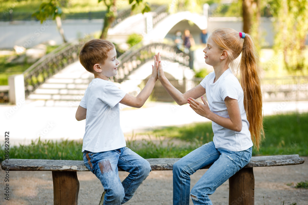 Fototapeta premium Cheerful children are playing in the park on a green bench.