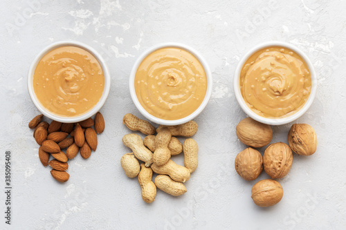 Walnut butter made of peanuts, almonds and walnut on a grey background.