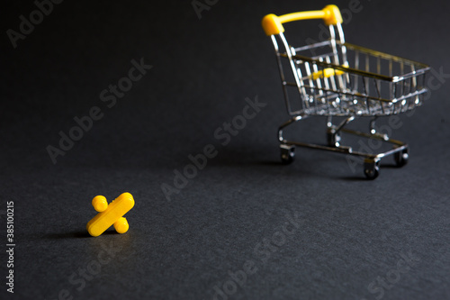 Yellow plastic sign percent on a black background with the shopping cart. Black Friday, discount percentage, shopping, buying and selling, promotion. Space for text