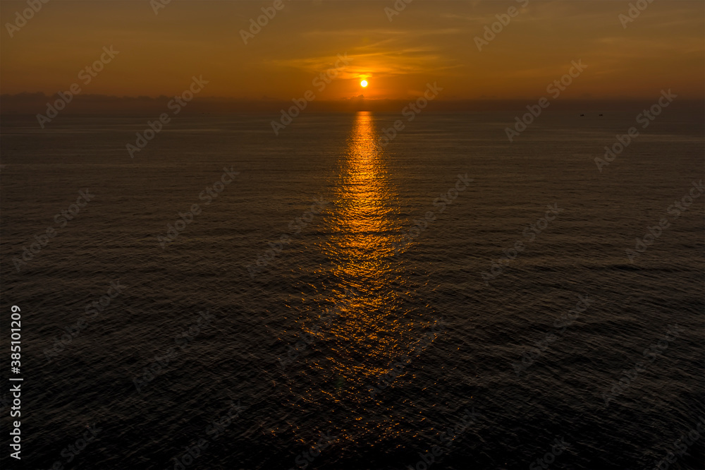 A sunset across the sea approaching Phuket island, Thailand