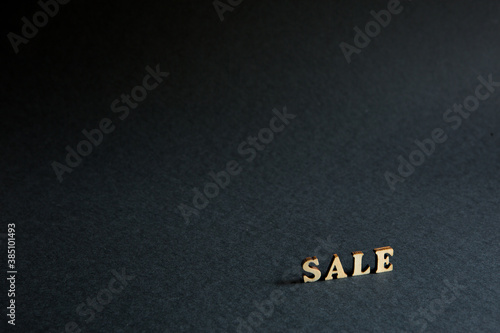 inscription "Sale" of wooden letters on a black background. Black Friday, discounts, sale, shopping, interest sign. Space for text