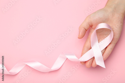 Breast cancer concept. Female hand holding pink ribbon