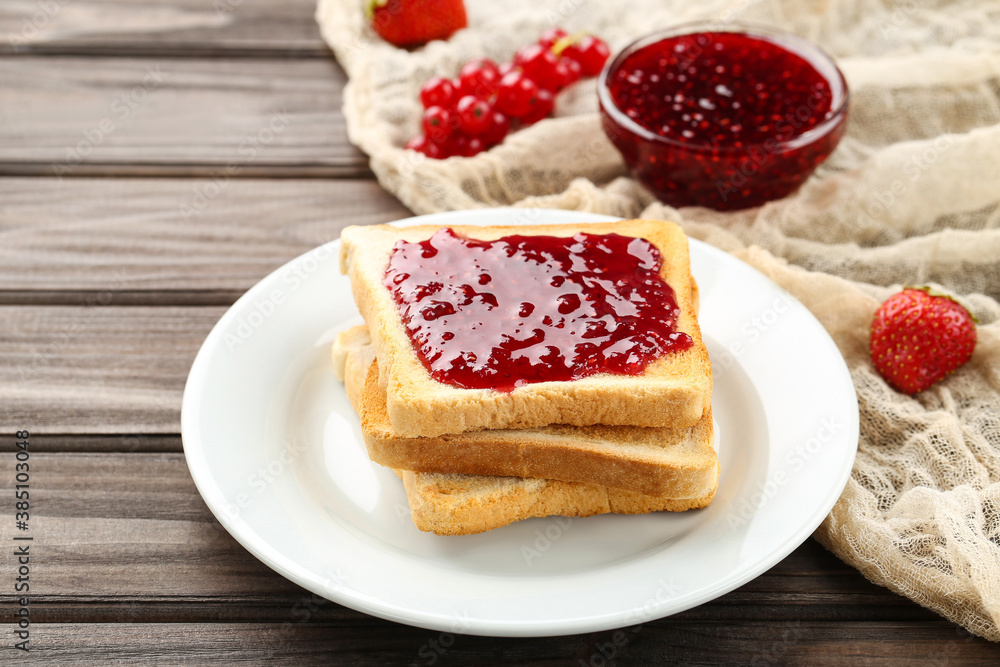Toast with raspberry jam in plate on wooden table Toast with raspberry jam in plate on wooden table