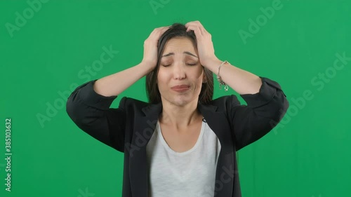 Horrible, stress, shock. Female portrait isolated at green screen background. Young emotional surprised woman clasping head in hands. Human emotions, facial expression concept. Choma key footage photo