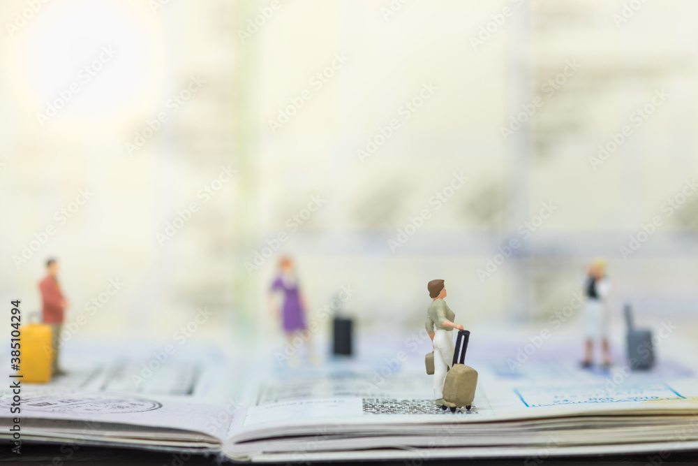 Fototapeta premium Travel Concept. Group of traveler miniature figure people with baggage on passport with immigration stamped and map as background.