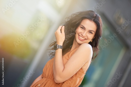 Free Download Portrait of a young happy attractive caucasian woman wearing summer dress looking at camera and smiling while standing on the city street - GFXLoad