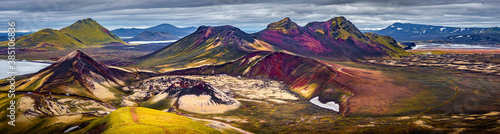 Panoramic unreal magic Icelandic landscape of colorful rainbow volcanic Landmannalaugar mountains, red and pink volcanic crater Stutur at famous Laugavegur hiking trail with dramatic sky, Iceland.
