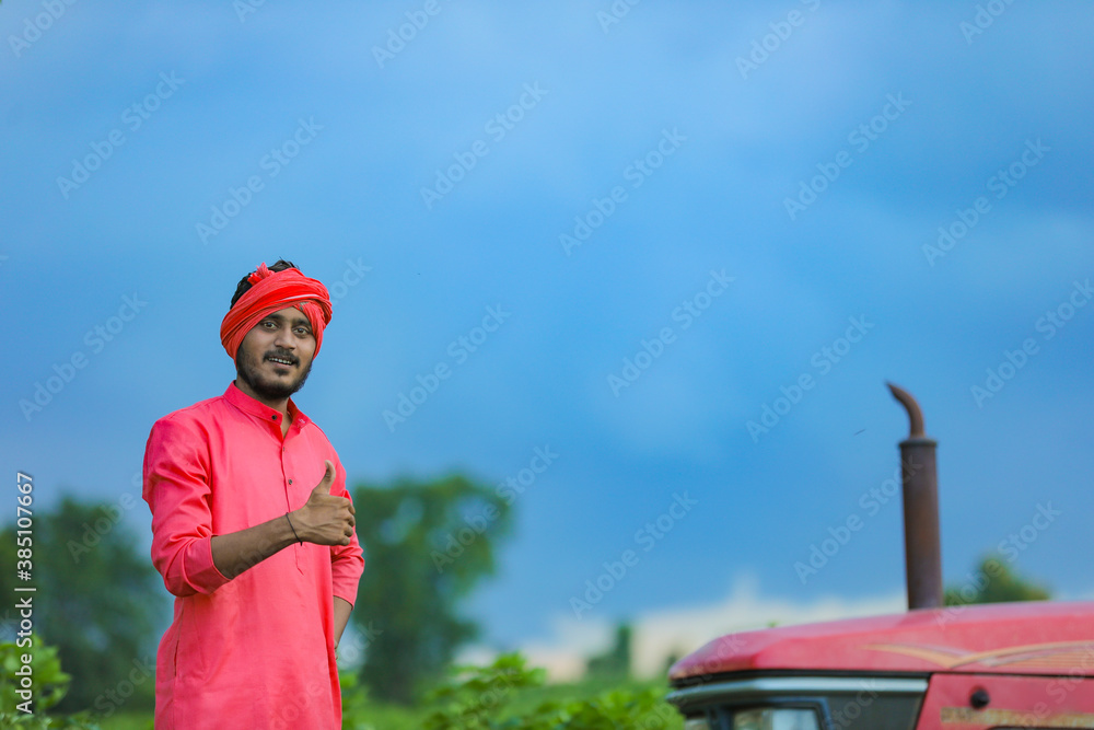 Obraz premium Technology and people concept, Portrait of young indian farmer with tractor