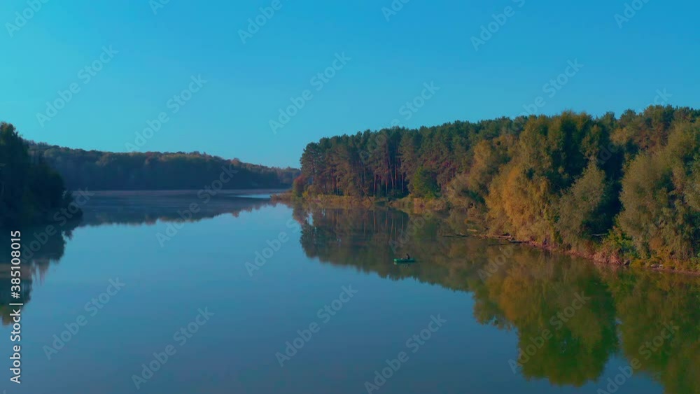 lonely fisherman on a boat. fishing boat in the middle of autumn lake dawn. fog over the lake. camera flies over reeds and foggy lake. evaporation over water lonely fisherman on a boat. fishing boat in the middle of autumn lake dawn. fog over the lake. camera flies over reeds and foggy lake. evaporation over water