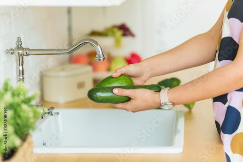 .female hands holding green vegetables over the sink