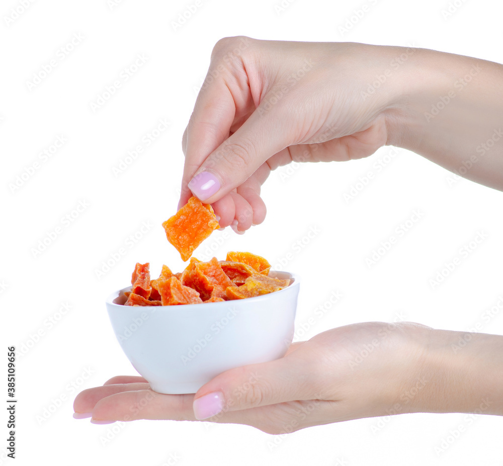 Hand holding candied dried pumpkin in white bowl on white background isolation Hand holding candied dried pumpkin in white bowl on white background isolation