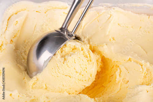 Extreme close up of some vanilla ice cream being scooped up by a mechanical scoop