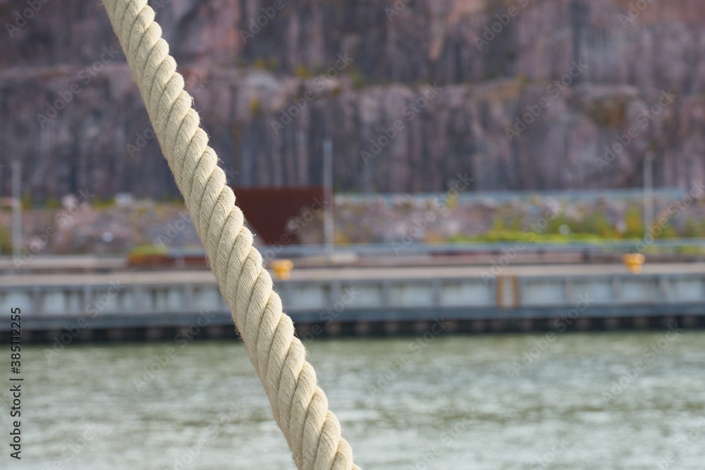 Naklejka premium Mooring rope with blurred river on the background.