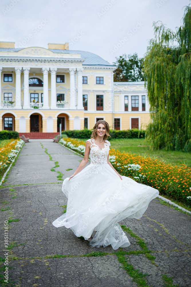 beautiful girl bride in a white dress with a train and a walk turned against the background of a large house with columns on their wedding day beautiful girl bride in a white dress with a train and a walk turned against the background of a large house with columns on their wedding day