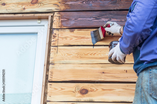 Wallpaper Mural Daylight. a person with the help of a brush applies to the facade of a wooden house, a special agent to extend the life of the building. Torontodigital.ca