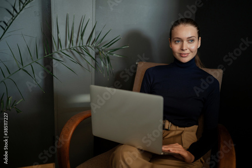 Thinks about a successful career in business. young woman of Caucasian appearance works reads an article writes plays on a laptop computer, sits in a comfortable chair, modern clothes for the office.