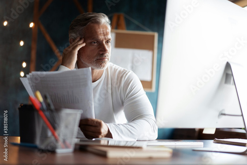 Fotografia Casual Grey-haired businessman looking through paper documents