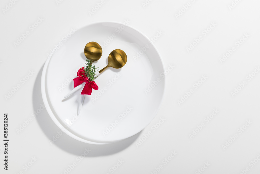 Gold spoons with red ribbon on a white plate - Christmas Minimalism
