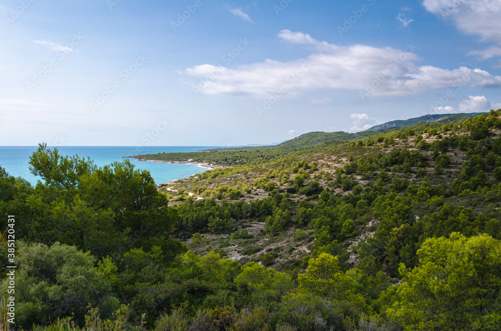 Natural landscape of Sierra de Irta Park beside the sea with its beautiful beaches on a summer day with blue sky and clouds, Peniscola, Castellon, Spain