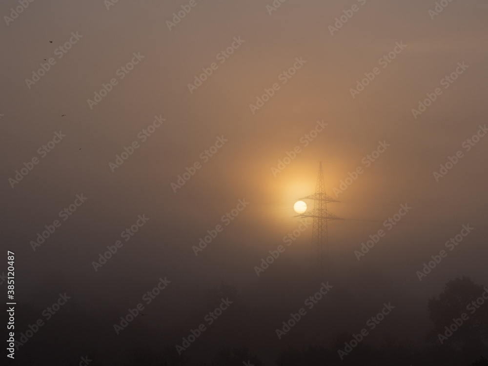  foggy landscape with a big power pole in the sunrise