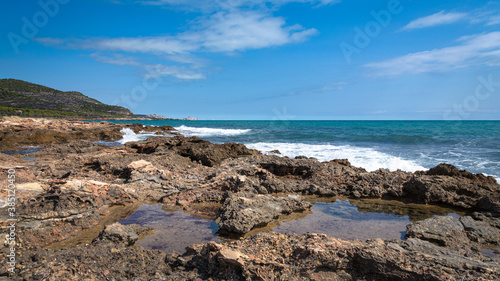 Sea waves break against the rocky coastline with Peniscola in the background, Castellon, Spain