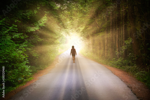 Artistic Render of a Girl Walking on a Road in the Enchanted Rainforest with light shinning. Road located in Tofino, Vancouver Island, BC, Canada. photo