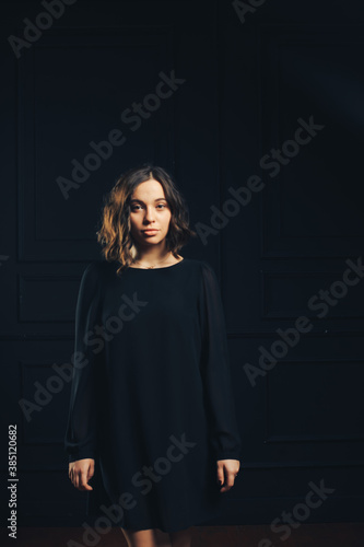 Girl in black dress in studio black wall