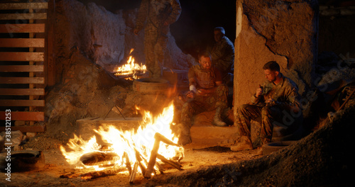 Military men resting around campfire
