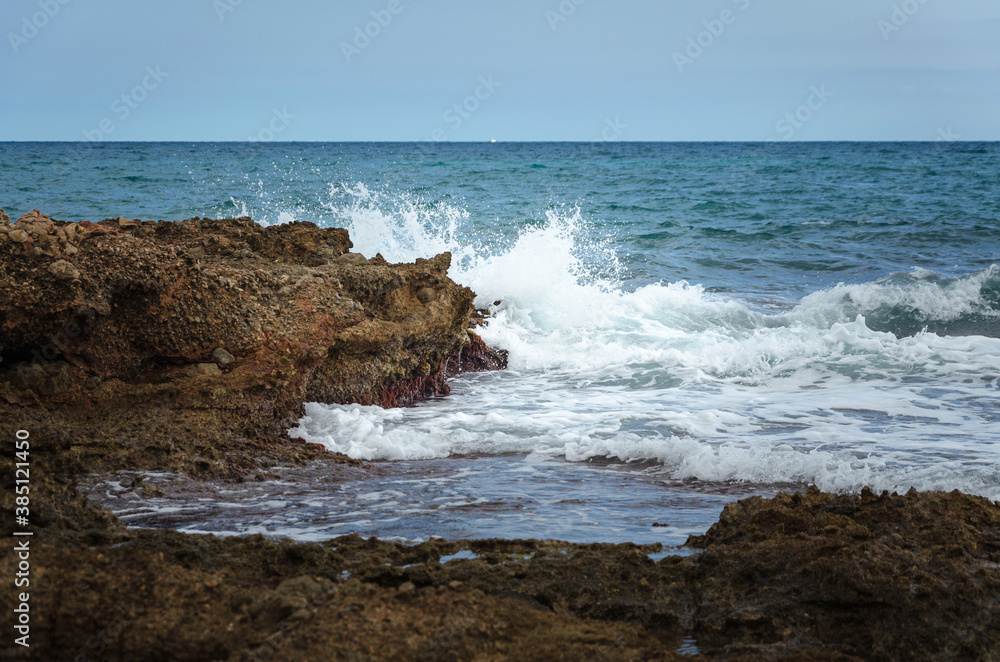 Sea waves break against the rocky coastline in Sierra de Irta Natural Park, Castellon, Spain