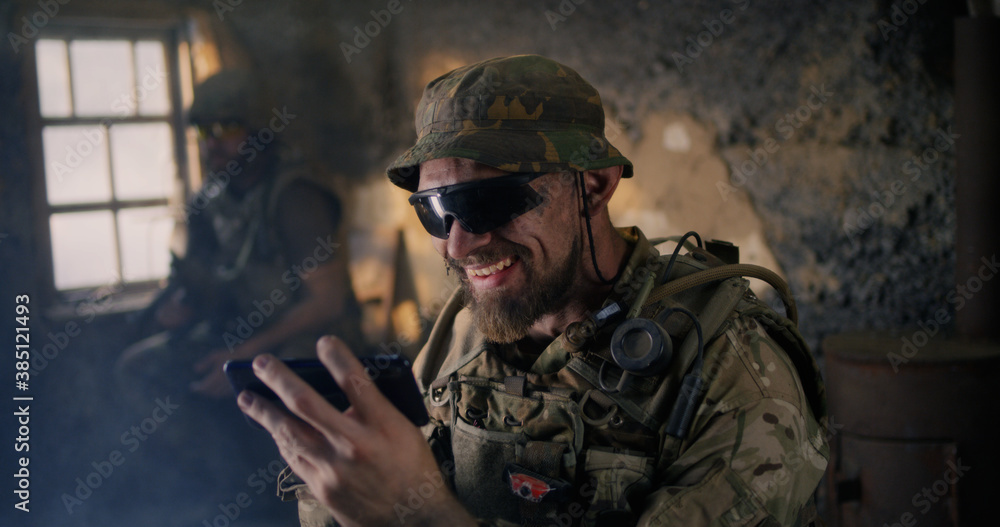 Military man using smartphone inside grungy building