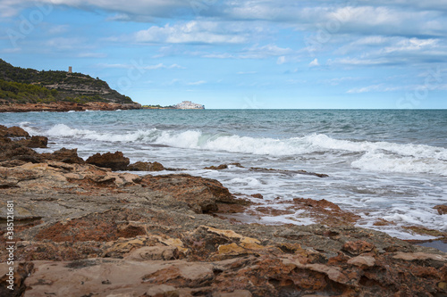 Sea waves break against the rocky coastline with Peniscola in the background  Castellon  Spain