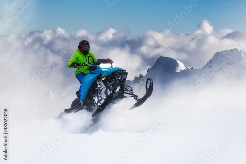 Adventurous Man Riding a Snowmobile in white snow. Epic Action Extreme Sport Composite. Background Mountains from British Columbia, Canada.