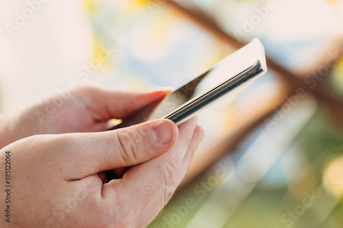 close-up shot of male hands holding smartphone with blank screen copy space for your text message or information content, against green nature background