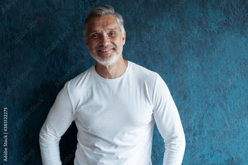 Casual Grey-haired Mature handsome man portrait over dark blue wall background Casual Grey-haired Mature handsome man portrait over dark blue wall background