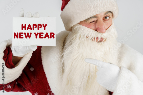Santa Claus holds a card with the text in his hands - HAPPY NEW YEAR