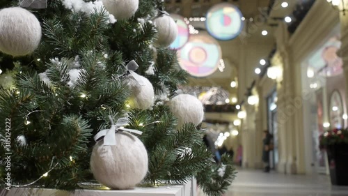 A girl touches a ball of thread hanging on a Christmas tree in a shopping center