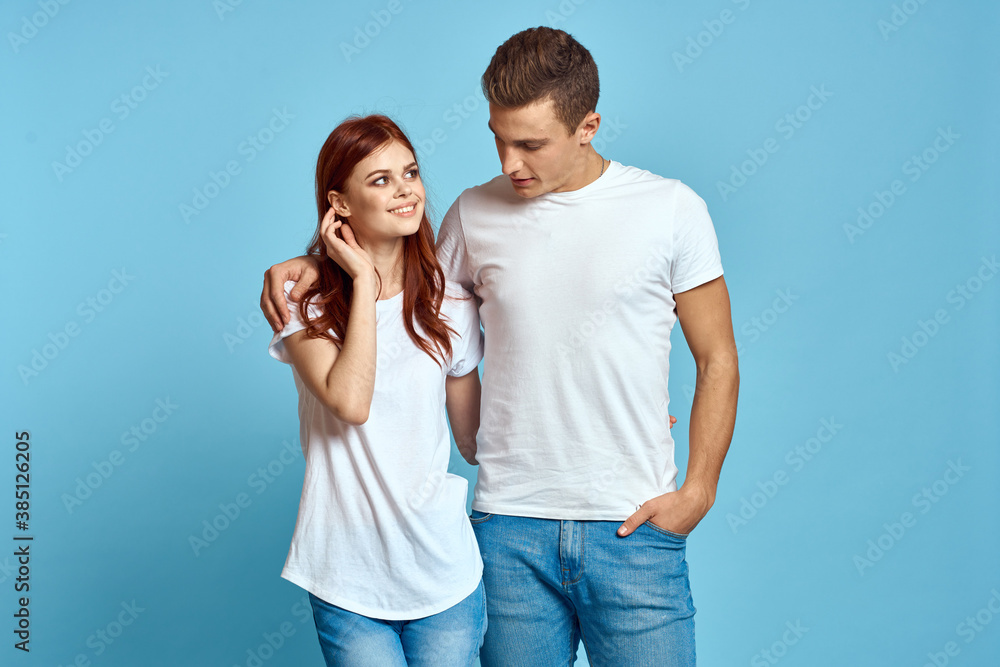 Fototapeta premium enamored man and woman in jeans and a T-shirt on a blue background hug each other and have fun
