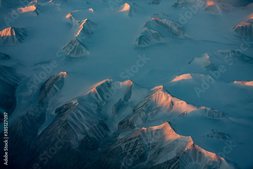 Aerial view of snowy mountain peaks of Greenland during sunset