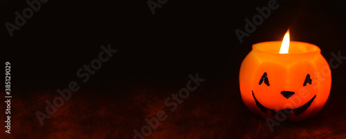Halloween pumpkin candle against the background of a black spider web.Banner, copy space for text