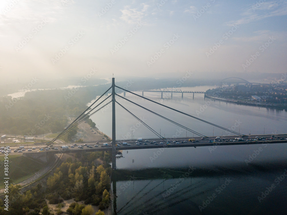 Aerial drone view. North bridge in Kiev in the rays of a sunny morning. Autumn haze in the air, cars are driving across the bridge.