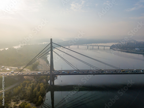 Aerial drone view. North bridge in Kiev in the rays of a sunny morning. Autumn haze in the air, cars are driving across the bridge. © Sergey