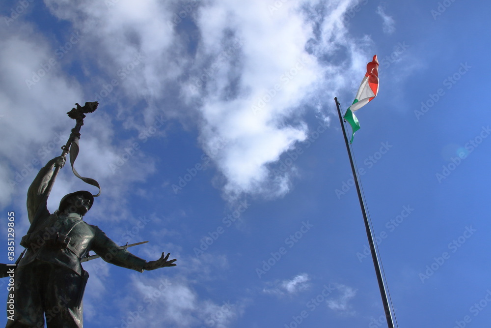 Fototapeta premium bronze statue of Italian partisan in front of the tricolor flag