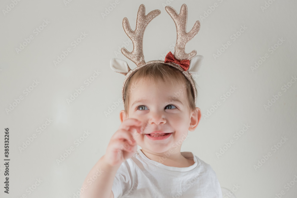 Little infant girl with shiny glitter rain deer horns costume. New year and christmas party celebration. Christmas holidays. Little infant girl with shiny glitter rain deer horns costume. New year and christmas party celebration. Christmas holidays.