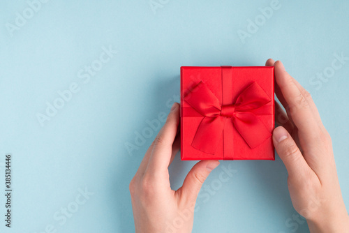 Fototapeta Naklejka Na Ścianę i Meble -  Best gift on birthday concept. Top above overhead close up first person view photo of female hands giving getting sending small vivid box isolated on pastel color background with empty space